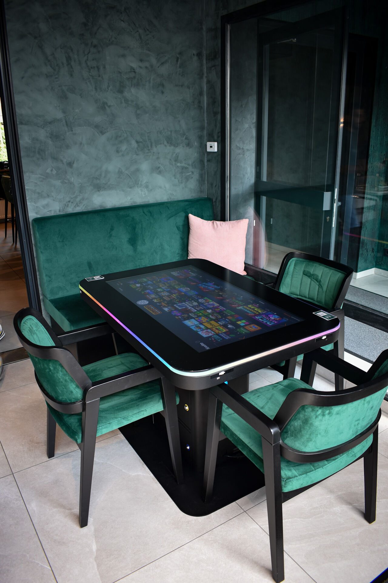 Leuchtender LED-Spieltisch zwischen Samtsesseln in Smaragdgrün